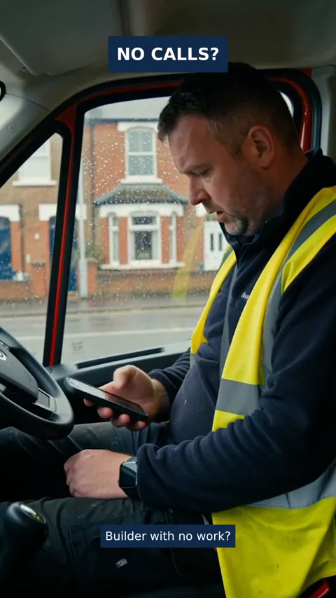 Builder sitting in his van looking at his phone